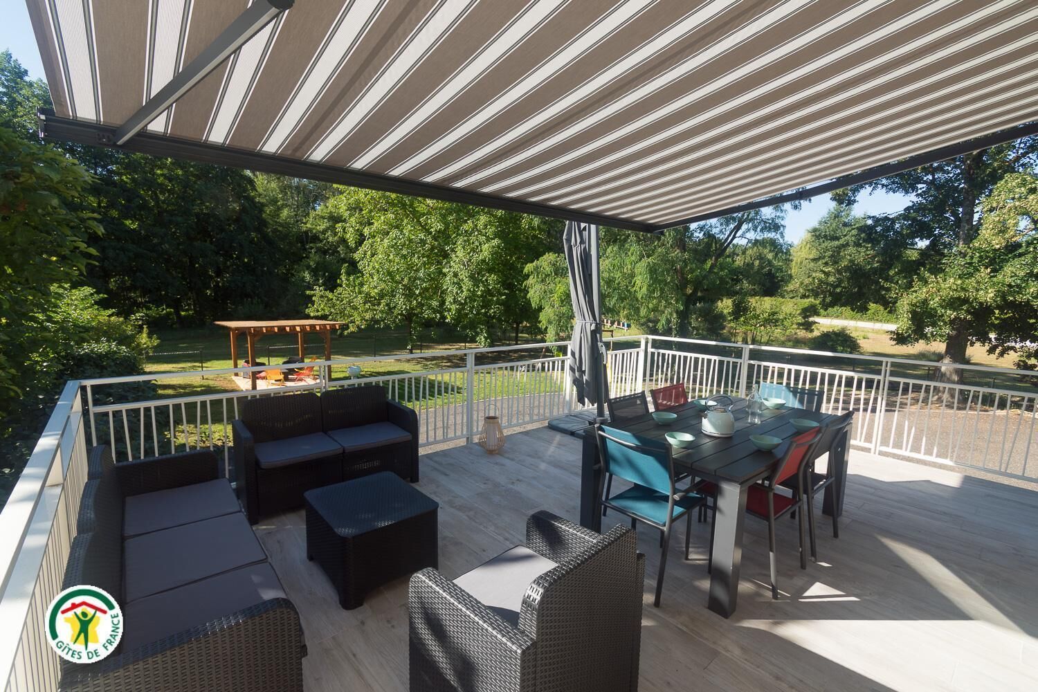 En udendørs terrasse med et overdækket siddeområde, et spisebord og en pergola.
