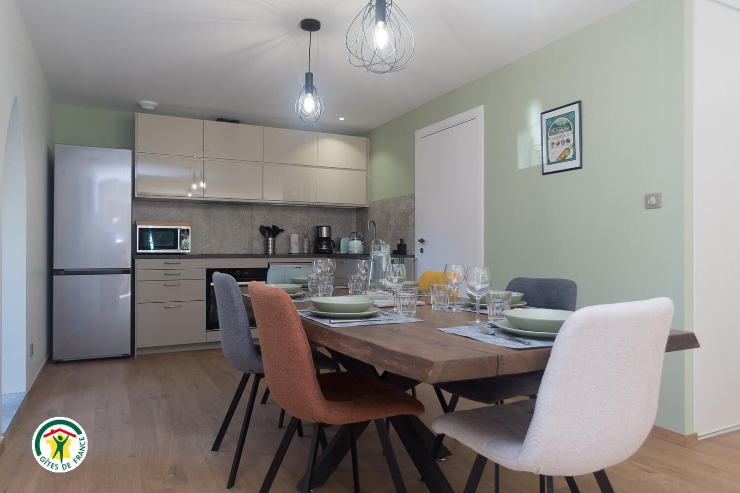 A modern kitchen with a dining area, featuring a refrigerator, microwave, and a dining table set with chairs.