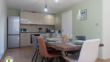 A modern kitchen with a dining area, featuring a refrigerator, microwave, and a dining table set with chairs.