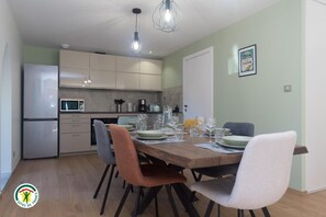 Eine moderne Küche mit Essbereich, inklusive Kühlschrank, Mikrowelle und einem Esstisch mit Stühlen.