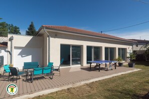 Ein Wohnhaus mit Terrasse, Sitzgelegenheiten im Freien und einem Tischtennisch.
