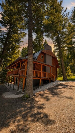 A cabin with a wooden deck, surrounded by trees. - Sagebrush Meadows+Hotub+WiFi+20minsYellowstone (Island Park)