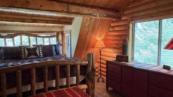 A log cabin interior with a wooden bench, a table, and a lamp.