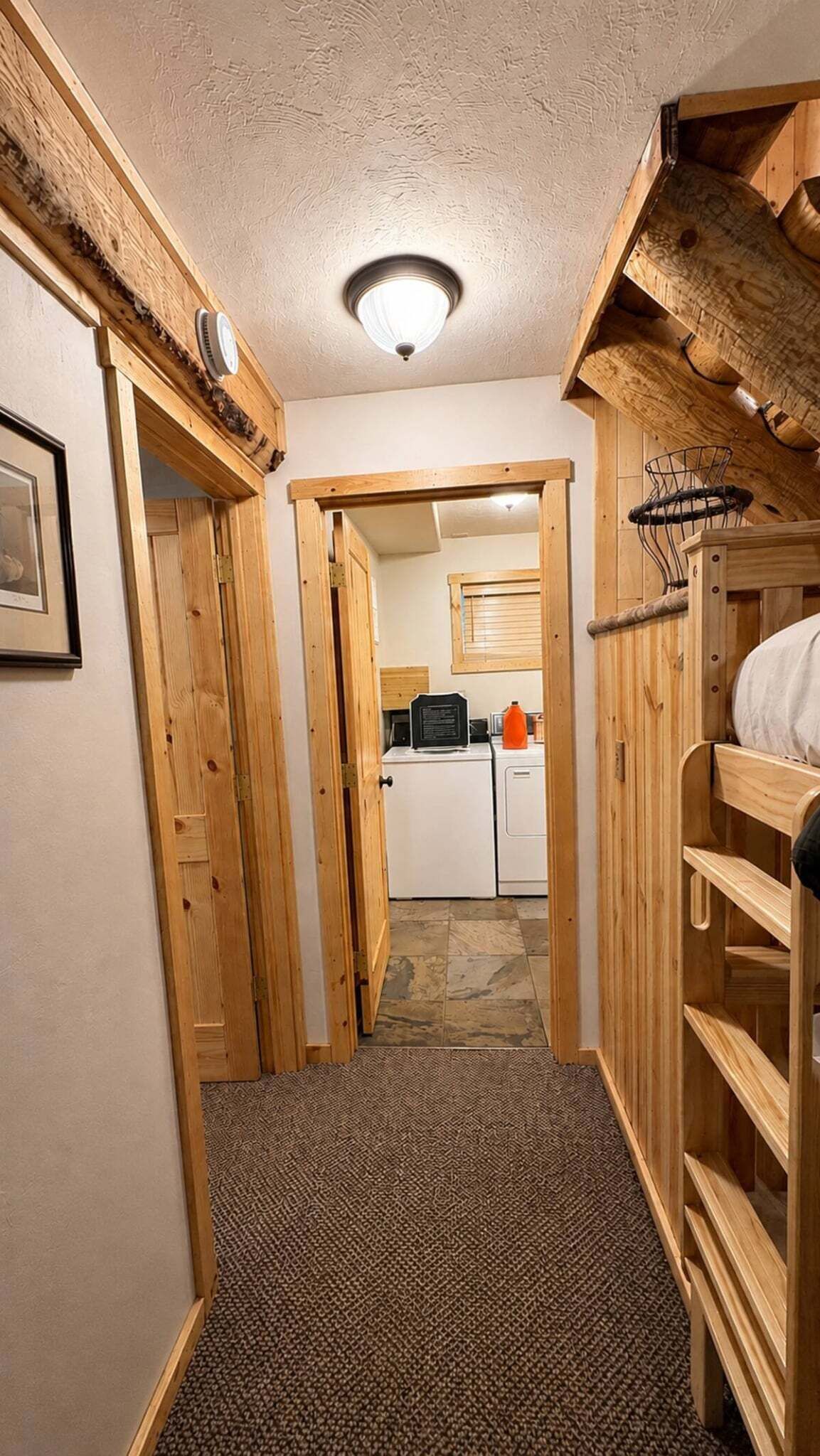 Ein schmaler Korridor mit Holzwänden und Teppichboden, der zu einem Küchenbereich mit Kühlschrank und Spüle führt.