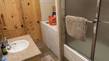 A bathroom with a shower, toilet, sink, and wooden cabinets.