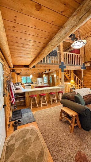 L’intérieur d’une cabane en rondins comprend une cuisine, un coin repas et une chambre à coucher située en mezzanine.