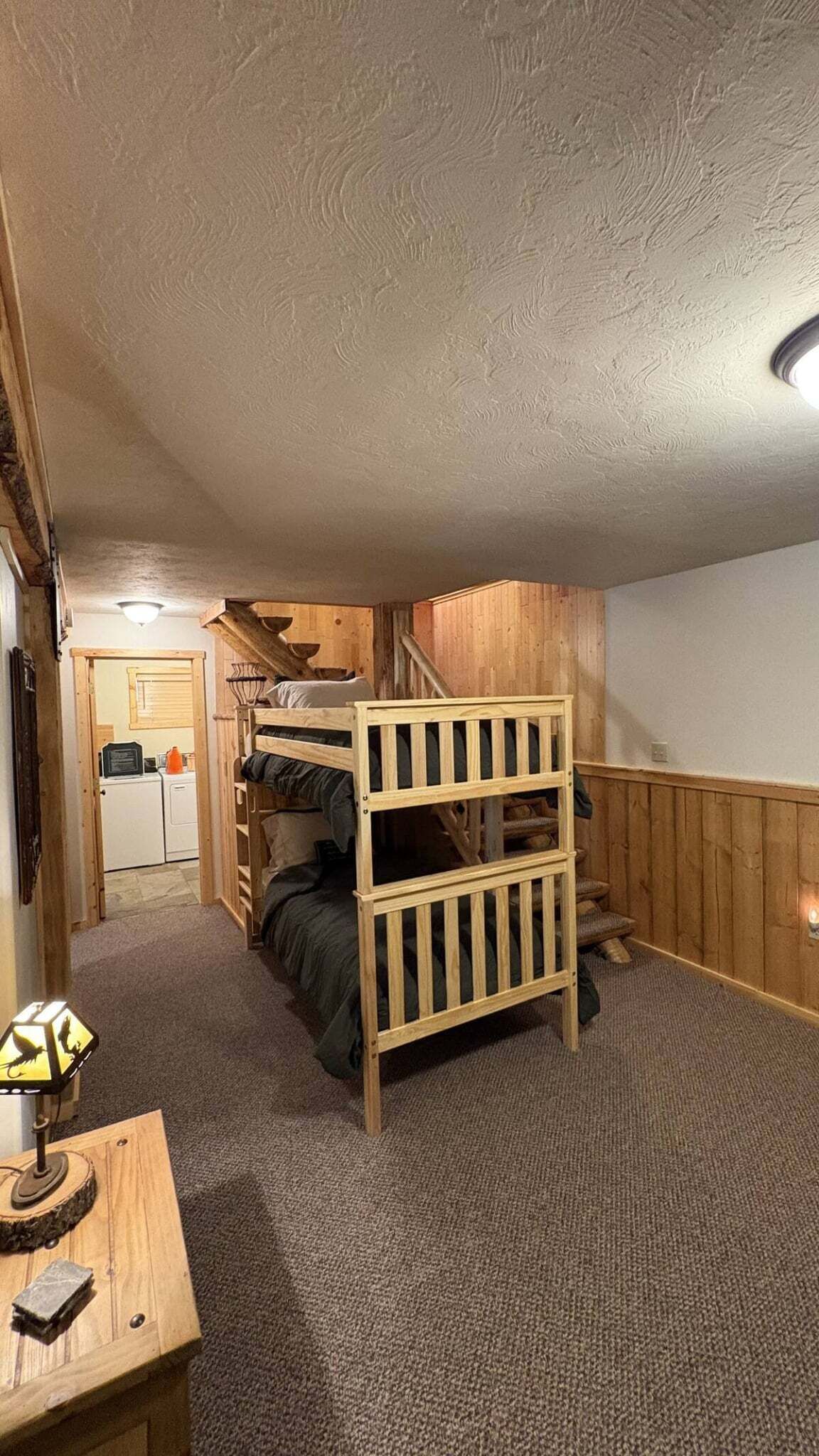 A compact room with bunk beds, a small table, and a staircase leading to an upper level.