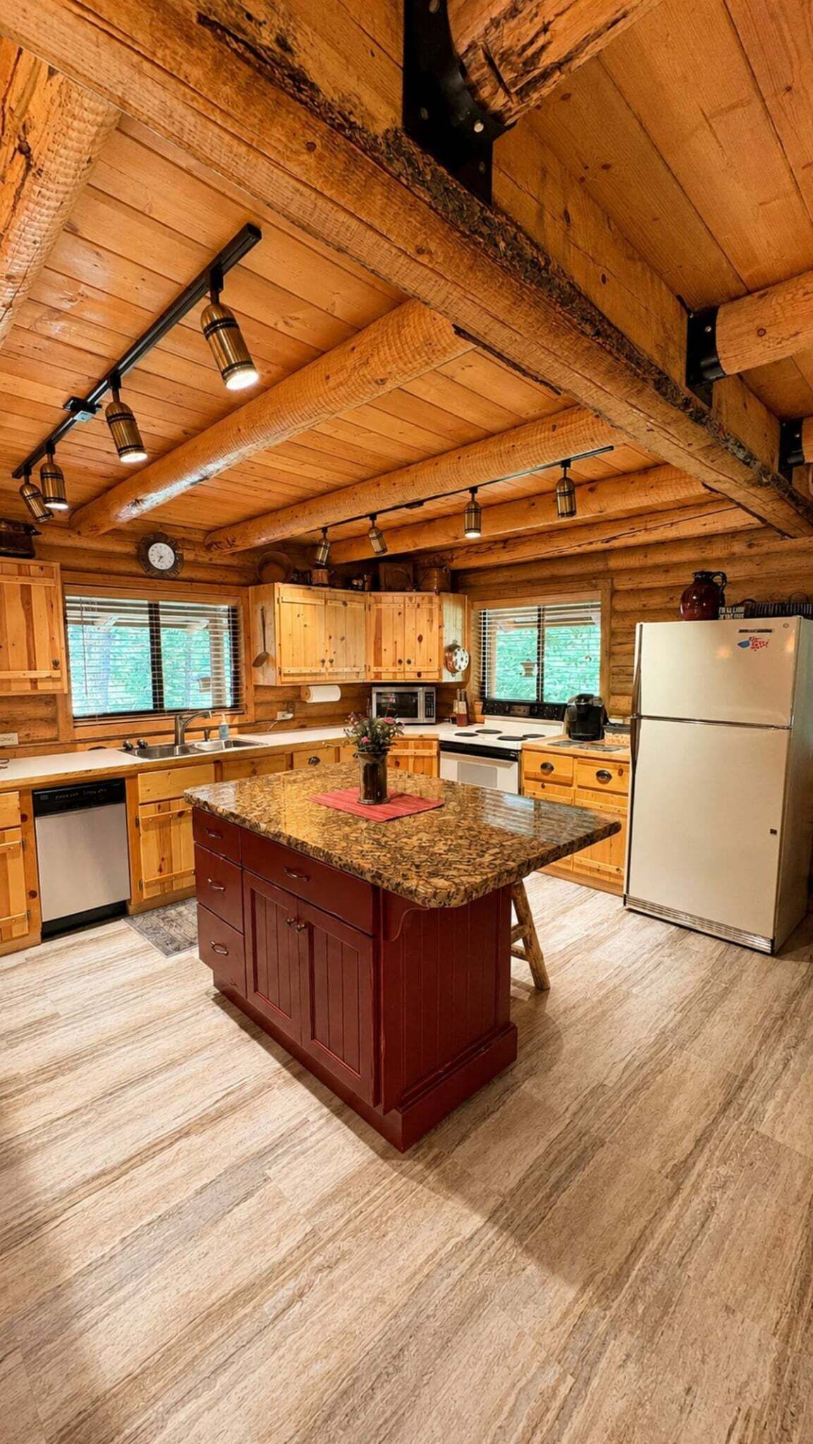 A kitchen with wooden cabinets, a granite countertop island, and a refrigerator.