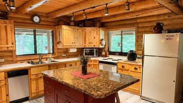 A kitchen with wooden cabinets, a granite countertop island, and a refrigerator.