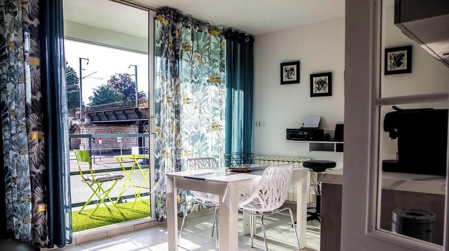 Una habitación con una mesa de comedor y sillas, un radiador, y vistas a un césped verde y un edificio exterior.