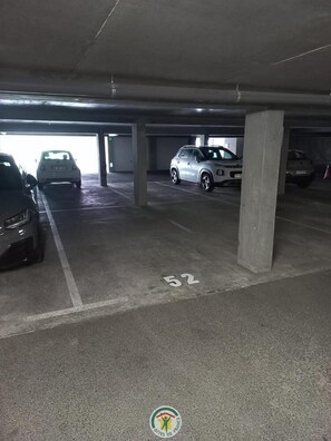 Eine Parkgarage mit Betonpfeilern, gekennzeichneten Parkfeldern und Fahrzeugen darin.