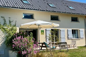 Ein Gebäude mit überdachter Außenbestuhlung, einem Schild, das auf ein Restaurant hinweist, und einem Fenster mit Fensterläden.