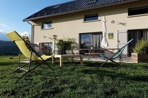 Talo, jossa on patio, jossa on pöytä, tuoleja ja pergola.