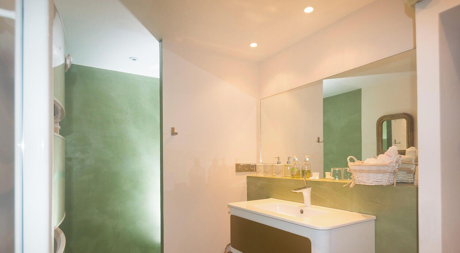 Ein Badezimmer mit einem weißen Waschbecken, einem Spiegel und Pflegeprodukten an der Wand.