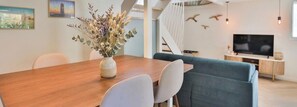 Ein modernes Wohnzimmer mit einem Holzespeisetisch, einem blauen Sofa, einem Fernseher und einer Treppe.