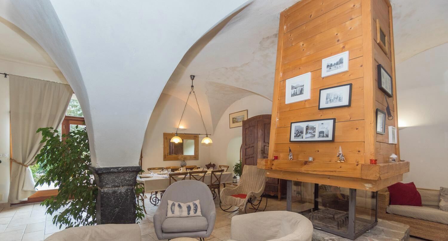A spacious living area with a dining table, comfortable seating, and a wooden wall with framed pictures.