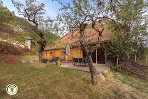 Una casa de fusta amb terrassa, mobles d'exterior i una paret de pedra.