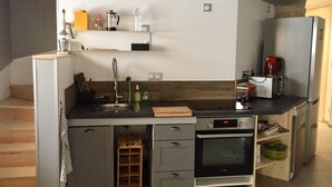 A compact kitchen with a built-in oven, a coffee maker, and a small refrigerator. - Le Nid in Chartreuse (SAINT PIERRE DE CHARTREUSE)