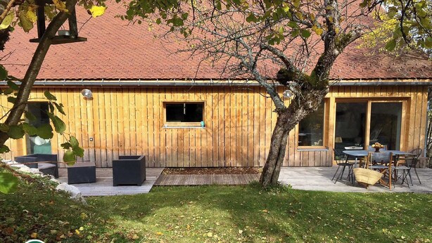 A wooden building with a red roof, a small window, and a patio with outdoor furniture. - Le Nid in Chartreuse (SAINT PIERRE DE CHARTREUSE)