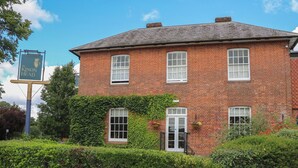 A two-story brick building with a signboard, windows, and a hedge in front. - Skylarks (Winchester)