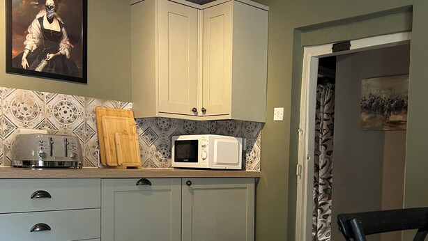 A kitchen with light-colored cabinets, a microwave, a toaster, and a wooden cutting board. - Skylarks (Winchester)