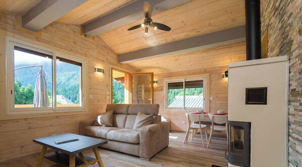 Ein gemütliches Blockhauss-Interieur mit einer Couch, einem Esstisch und einem Kamin.