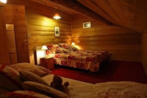 Ein gemütliches Zimmer mit Holzbalkendecke, einem Bett mit Steppdecke, einem Nachttisch und einem Wandbild.