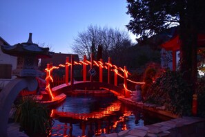 A traditional bridge with red lighting, a pond, and a statue. - At the Japanese Spring - 4**** (PIERRE CHATEL)