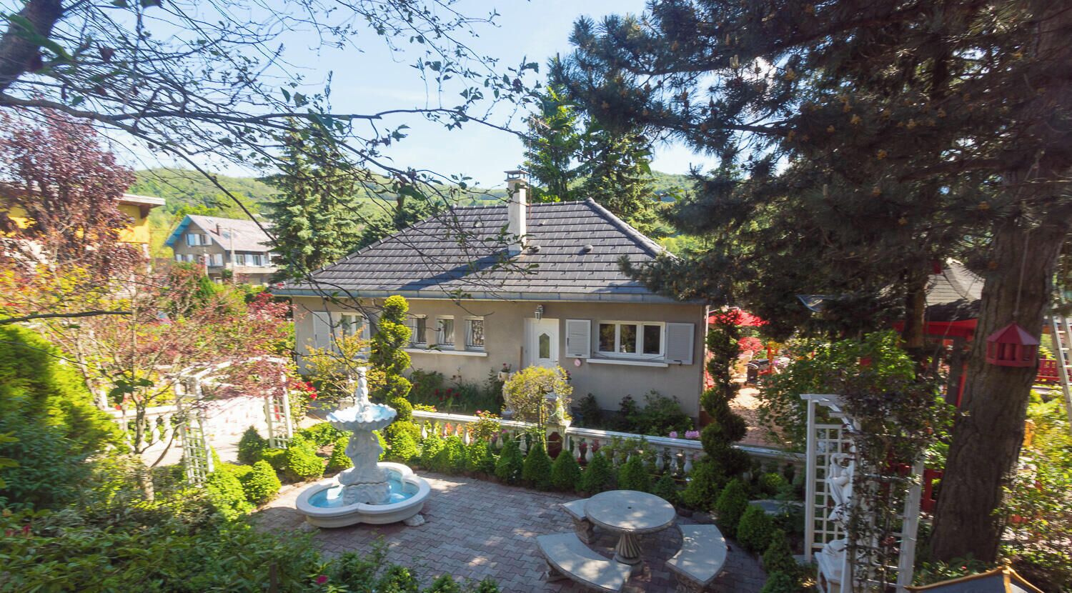 A house with a garden, a fountain, and a white fence.