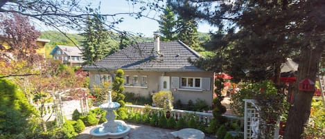 A house with a garden, a fountain, and a white fence.