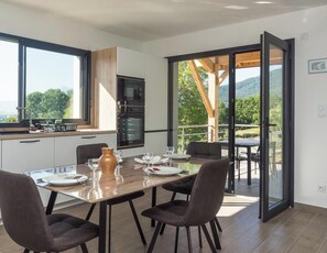 Eine moderne Küche mit Essbereich, großen Fenstern und Blick ins Freie.