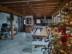 A spacious dining area with a wooden table and chairs, a kitchen in the background, and a decorated Christmas tree. - The 12 Summits - PONSONNAS (PONSONNAS)