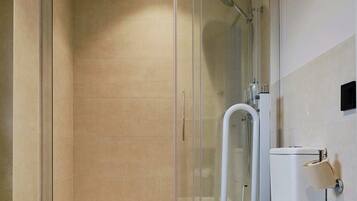 Un baño con cabina de ducha, inodoro y suelo de baldosas estampadas.