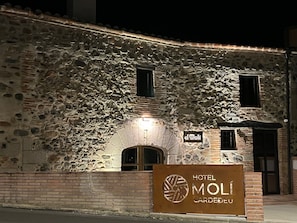 A stone building with a sign for Hotel Molí Cardeau.