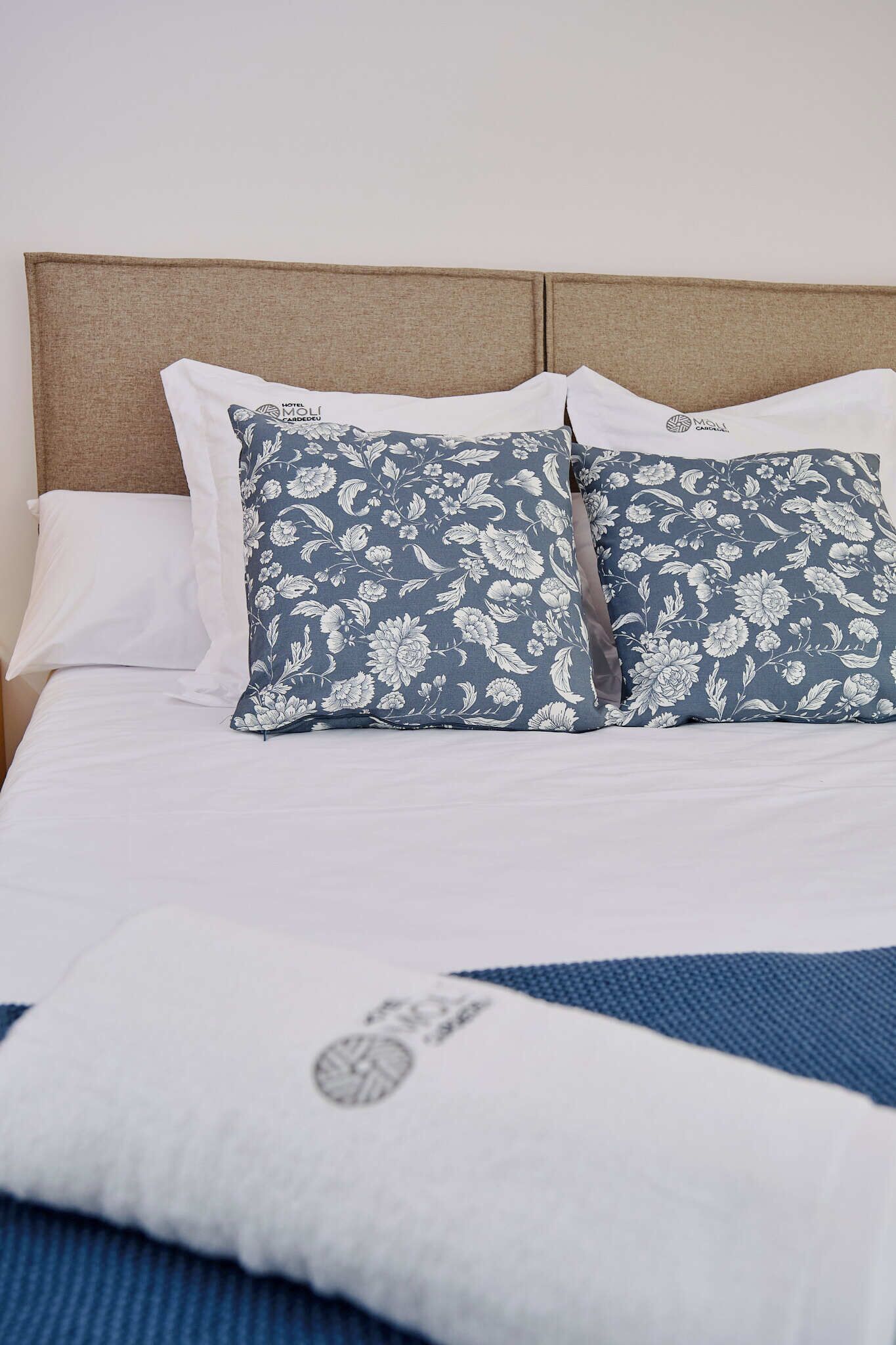 A bed with a headboard, two pillows with a floral pattern, and a blanket with a geometric design.