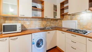 Una cocina compacta equipada con microondas, lavadora, lavaplatos y estufa.