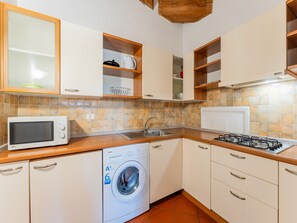 Eine kleine Küche mit Mikrowelle, Waschmaschine, Spüle und Herd.