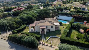 Una villa de estilo mediterráneo con piscina, rodeada de exuberante vegetación y colinas.