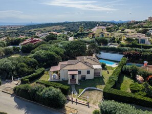 Eine mediterran gestaltete Villa mit Swimmingpool, umgeben von üppiger Vegetation und Hügeln.