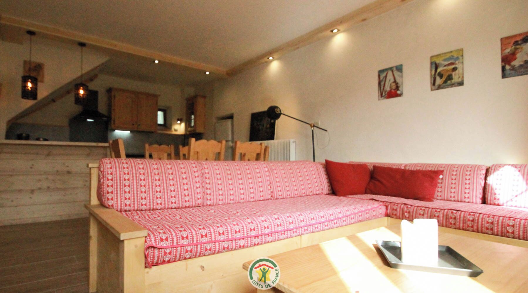 Un salón acogedor con un sofá rojo estampado, suelo de madera y una mesa de comedor con sillas.