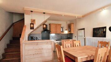 Una cocina con armarios de madera, una mesa de comedor con sillas y una escalera.