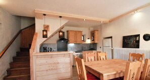Eine Küche mit Holzausstattung, einem Esstisch mit Stühlen und einer Treppe.