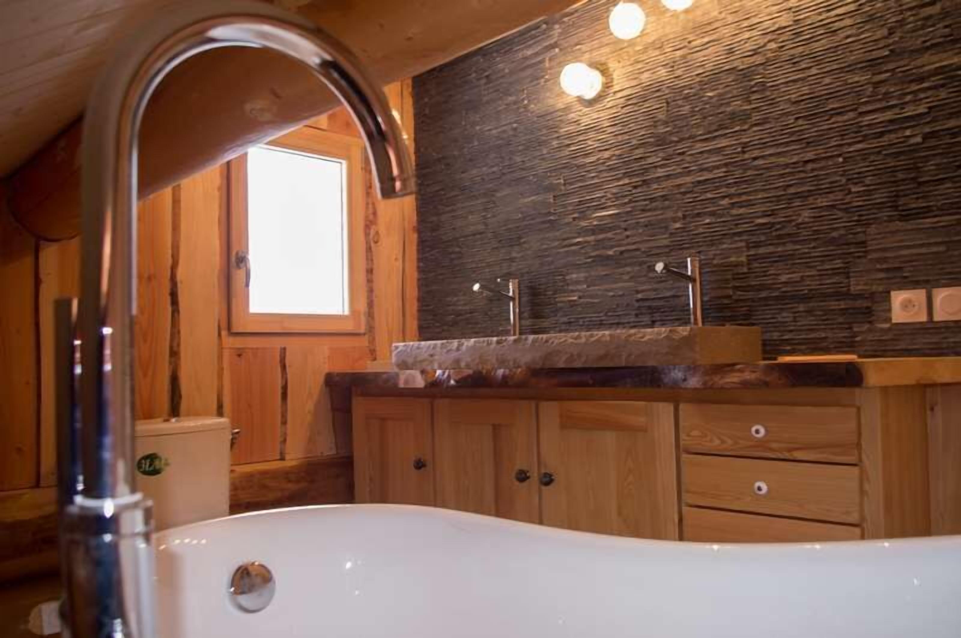 Une salle de bain avec une baignoire, des meubles en bois et un mur en pierre.