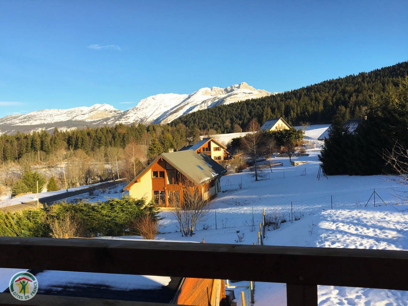 A snow-covered landscape with a wooden cabin and a mountain in the background.