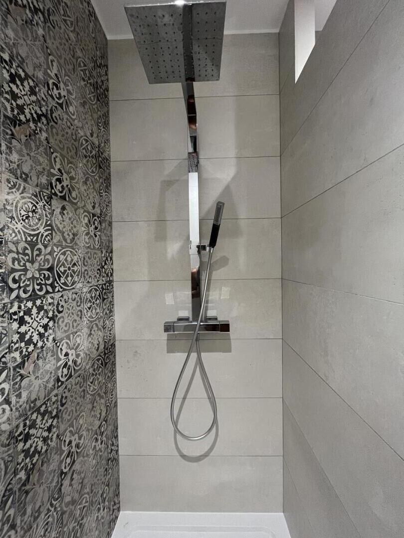 A shower with a modern design, including a square showerhead and a handheld showerhead.