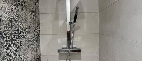 A shower with a modern design, including a square showerhead and a handheld showerhead.