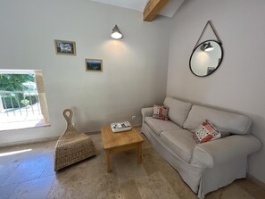 Ein Wohnzimmer mit einer Couch, einem kleinen Tisch, einem gewebten Pouf und einem Spiegel an der Wand.