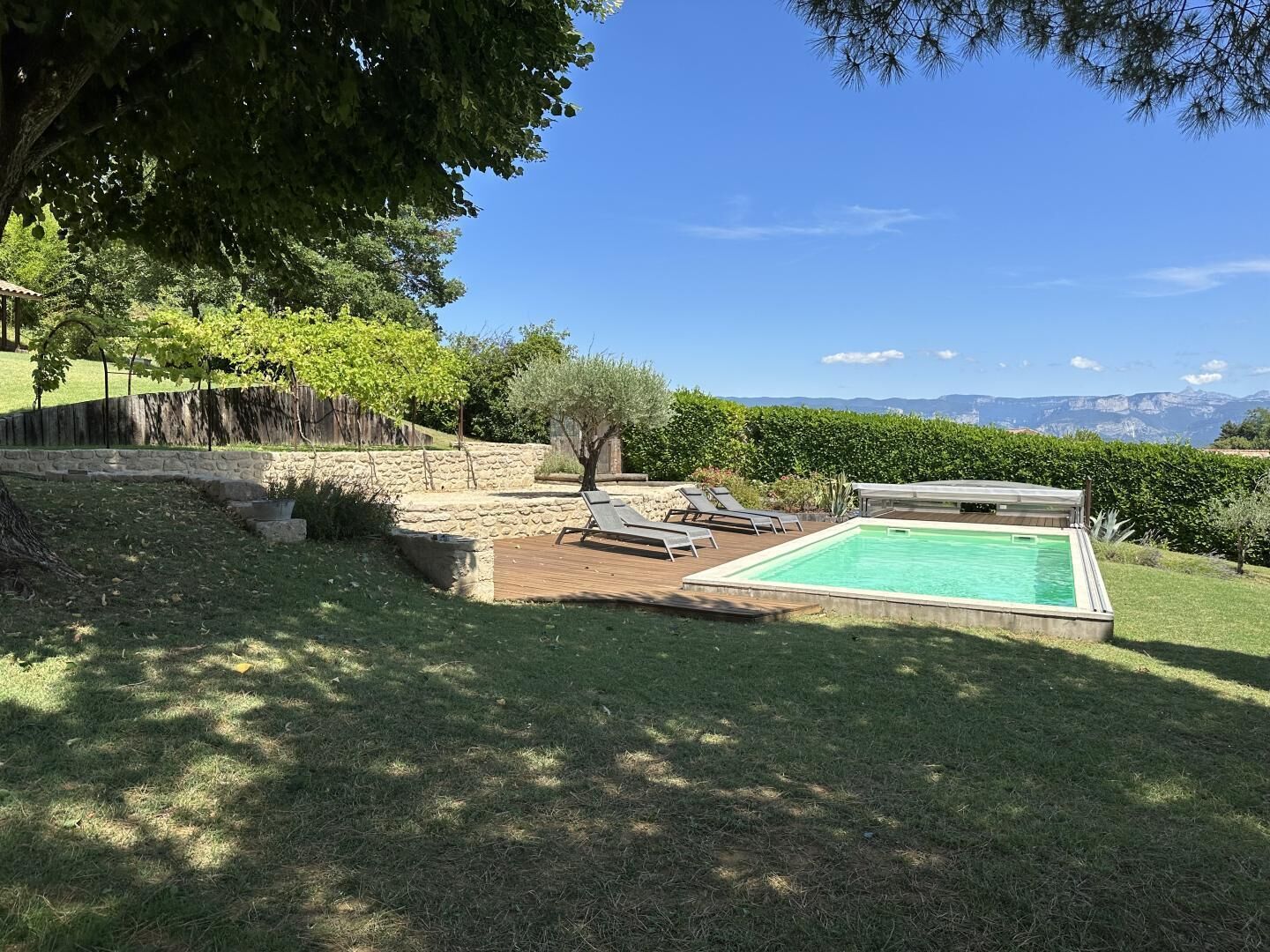 Un jardin avec une piscine, des murs en pierre et une vue sur les montagnes.