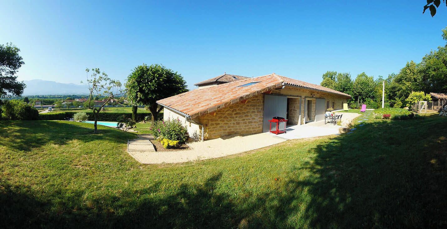 Une maison en pierre avec un toit en tuiles, une piscine et un jardin.