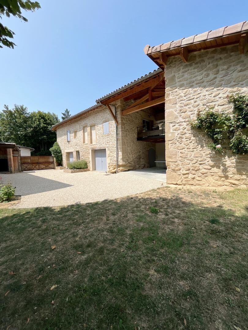 A stone building with a covered porch and a gravel driveway.